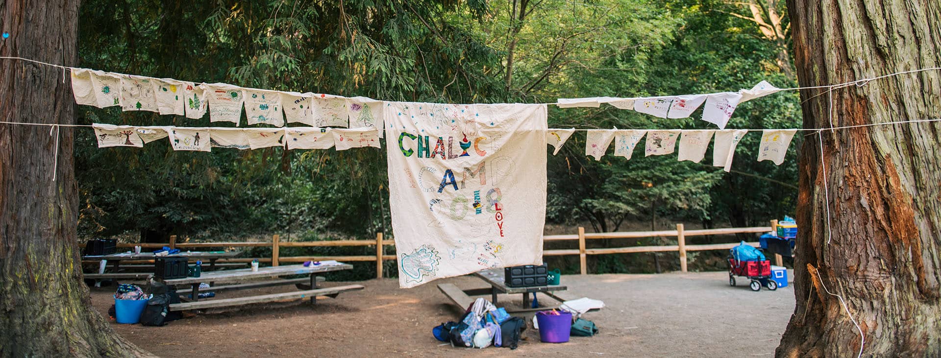 Hand drawn Chalice Camp banner strung between two trees